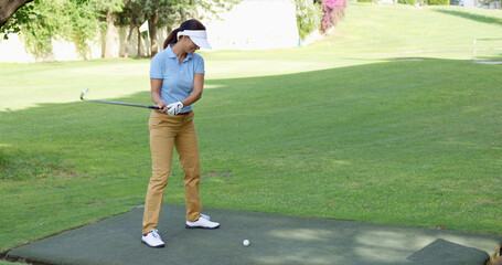 Young female golfer preparing to tee off at the start of a hole on a golf course  with copy space...