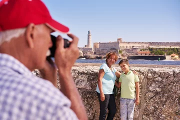 Abwaschbare Fototapete Havana Happy tourists on holidays. Hispanic people traveling in Havana, Cuba. Grandfather, grandmother and grandchild during summer travel, with senior man taking photos with camera