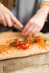 Woman cuts cherry tomatoes on a wooden board