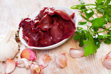 Image of raw rabbit liver with garlic and greens during cooking