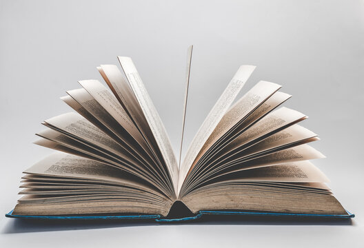 An old open story book on a white background with the pages fanning out.