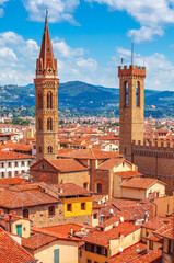 Obraz premium Tower of Palazzo Vecchio in Florence top view to tile roofs of old town. Blue mountains landscape on background. Italy.