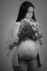 Portrait of pregnant young woman with a bouquet of white flowers.