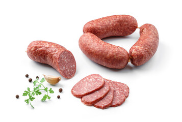 Stick of dried or smoked sausage, sliced salami with spices and fresh herbs isolated on white...