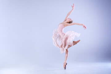 Naklejka premium Young ballerina is dancing in a white studio full of light