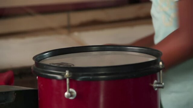 Hands of a Young Boy Playing Drum and Cowbell at his Home in Argentina. Close Up.