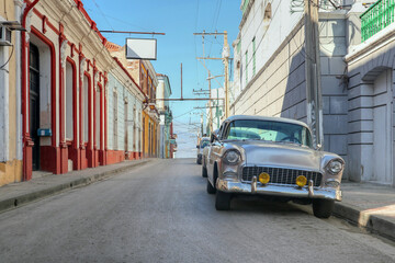 an old classic car on the colorful street of Santiago De Cuba 