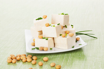 Tofu and soybeans on green background. Natural vegan and vegetarian eating.