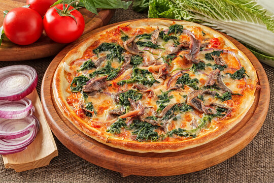 Pizza with anchovies, spinach, tomatoes and cheese
