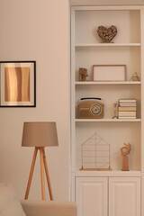Stylish shelves with different decor elements and lamp in room. Interior design