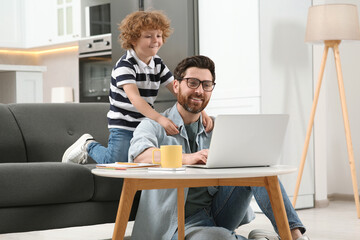 Man with laptop working remotely at home. Father and son at desk