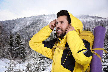 Happy tourist with backpack in snowy mountains