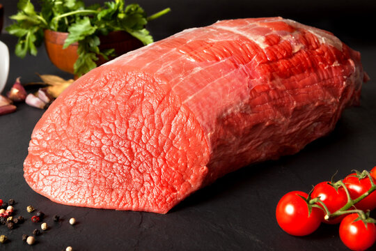 Still life raw beef round over black ground