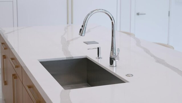 Close up of washing sink being mounted into white island counter with marble glossy surface. Design interior of modern style kitchen in new house