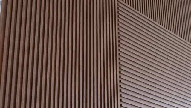 Fragment of vertical and horizontal brown slatted panels of dark wood used in wall interior. Trendy loft style in modern house