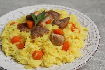 Delicious pilaf with meat served on light grey table, closeup