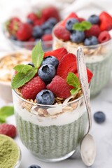Tasty matcha chia pudding with oatmeal and berries on white marble table, closeup. Healthy breakfast
