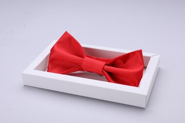 Stylish red bow tie in box on white background