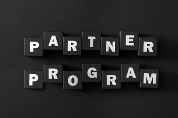 Words Partner Program made of cubes with letters on black background, top view