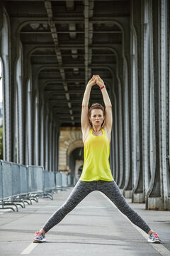 Outdoors fitness in Paris. Full length portrait of young sportswoman stretching on Pont de Bir-Hakeim bridge in Paris