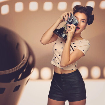 Happy beautiful young woman taking picture with retro photo camera. Surprised expression. Film background.