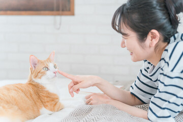 家のベッドルームでペットの猫の鼻を触るアジア人女性(アニマルセラピー・スキンシップ)
 - obrazy, fototapety, plakaty