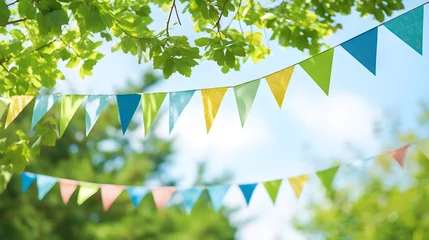 Papier Peint photo Jardin colorful pennant string decoration in green tree foliage on blue sky, summer party background template banner with copy space 