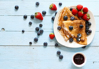 Delicious Crepes Breakfast with Dramatic light over a vintage wood background. An healthy meal of Pancakes with marmalede, blueberries and strawberries.