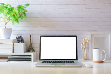 Laptop computer, coffee cup, potted plant and picture frame on creative workplace. Blank screen for your advertising text.