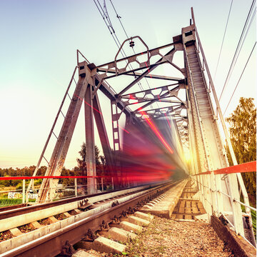 Highspeed train moves fast on the bridge at sunsset.