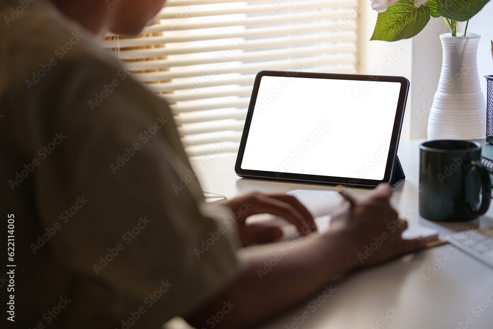Aufkleber back view of young businessman working on new project with computer tablet at his home office..