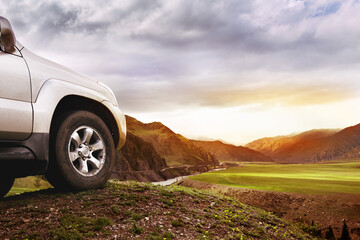Fototapeta na wymiar Offroad car concept. Big car wheel on background of mountains and sunset
