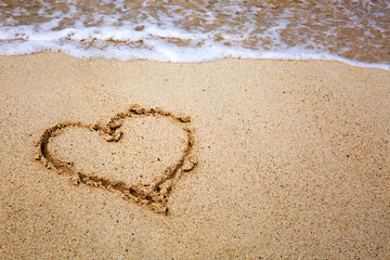 Heart drawn in the sand of sea beach .