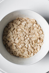 nigerian egusi seeds in a white bowl, shelled melon seeds in a bowl, nigerian melon seeds, pumpkin seeds for cooking