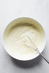 Creamed butter, sugar and egg until pale in a white mixing bowl, the process of making a cake, mixing butter, sugar and egg to make a cake