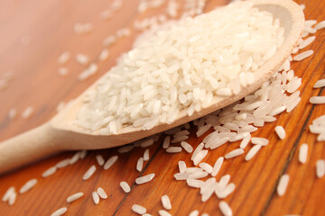 Close-up of rice in a wooden spoon on a wooden surface