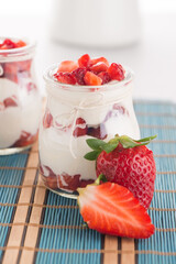 Strawberries desert with cream served on glass cups over table top.