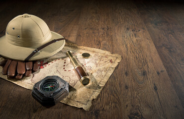 Old treasure map with colonial style pith hat, bras telescope and compass.