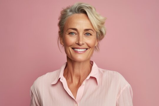 Portrait of smiling senior woman looking at camera isolated over pink background