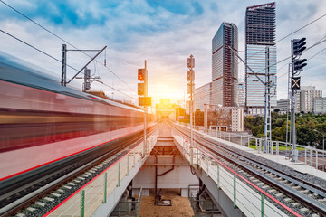 Modern high-speed train arrives to the station at sunset time.