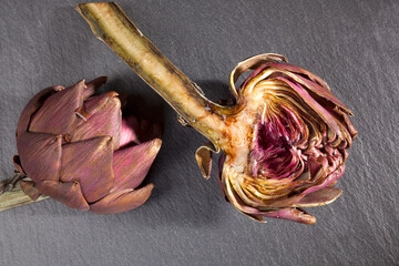 Fresh artichoke on black stone background, top view. Culinary healthy vegetable eating.