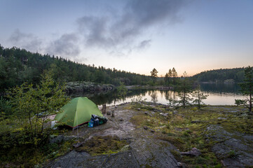 Late evening landscape view of Ladoga lake islands and small tourist tent on the rocks. Karelia, Russia.