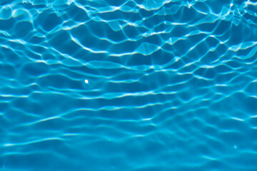 Blue water with ripples on the surface. Defocus blurred transparent blue colored clear calm water surface texture with splashes and bubbles. Water waves with shining pattern texture background.