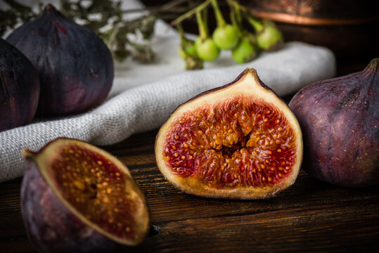 Half ripe and juicy fig lying on rustic table. Seasonal and exotic fruit