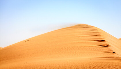Wind blowing sand off the top of a dune in Desert Conservation Reserve near Dubai, UAE