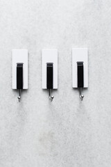 Sticky adhesive hooks on a white wall, white and black adhesive wall hooks on a grey wall