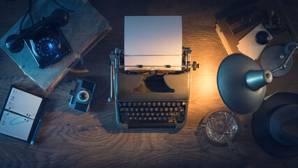 Retro journalist's desk 1950s style with vintage typewriter, phone and lamp at night time, top view