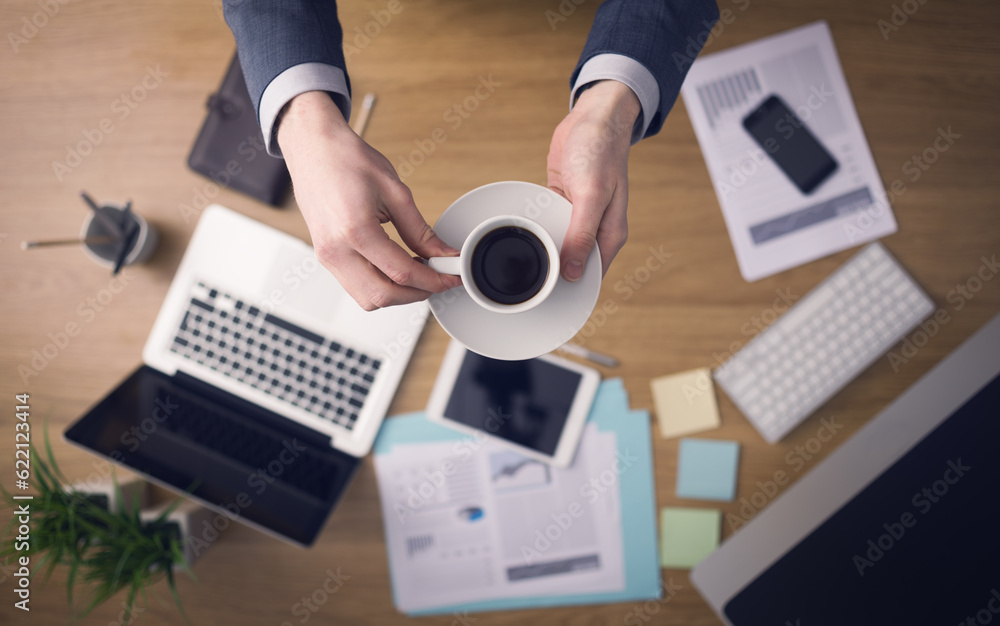 Poster professional businessman having a coffee break while working at his office desk, hands close-up top 