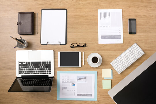 Businessman's tidy desktop and work tools with paperwork, computer, touch screen devices and stationery on a wooden surface, top view