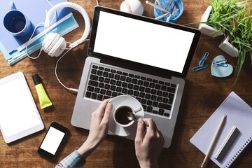 Teenager desktop mock up with laptop, tablet, mobile smart phone and hands holding a cup of coffee